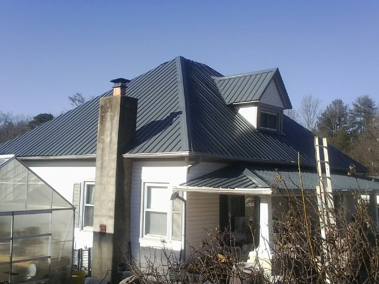 Dark blue standing seam metal roof on a white farmhouse with dormer — Slate & Tile Roof Repair by Roofing Brothers in Longmeadow