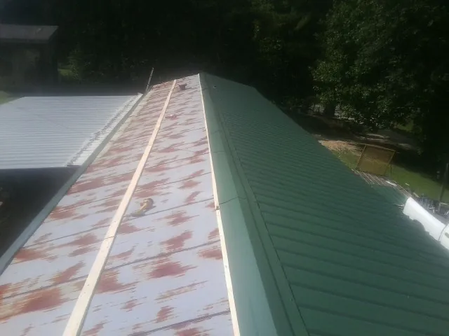 Old rusted panels beside newly installed green metal roofing — Wind Damage Roof Repair by Roofing Brothers in Longmeadow