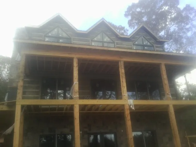Dormers and porch framing on a large log home under construction — Roof Coating work by our crew in Longmeadow
