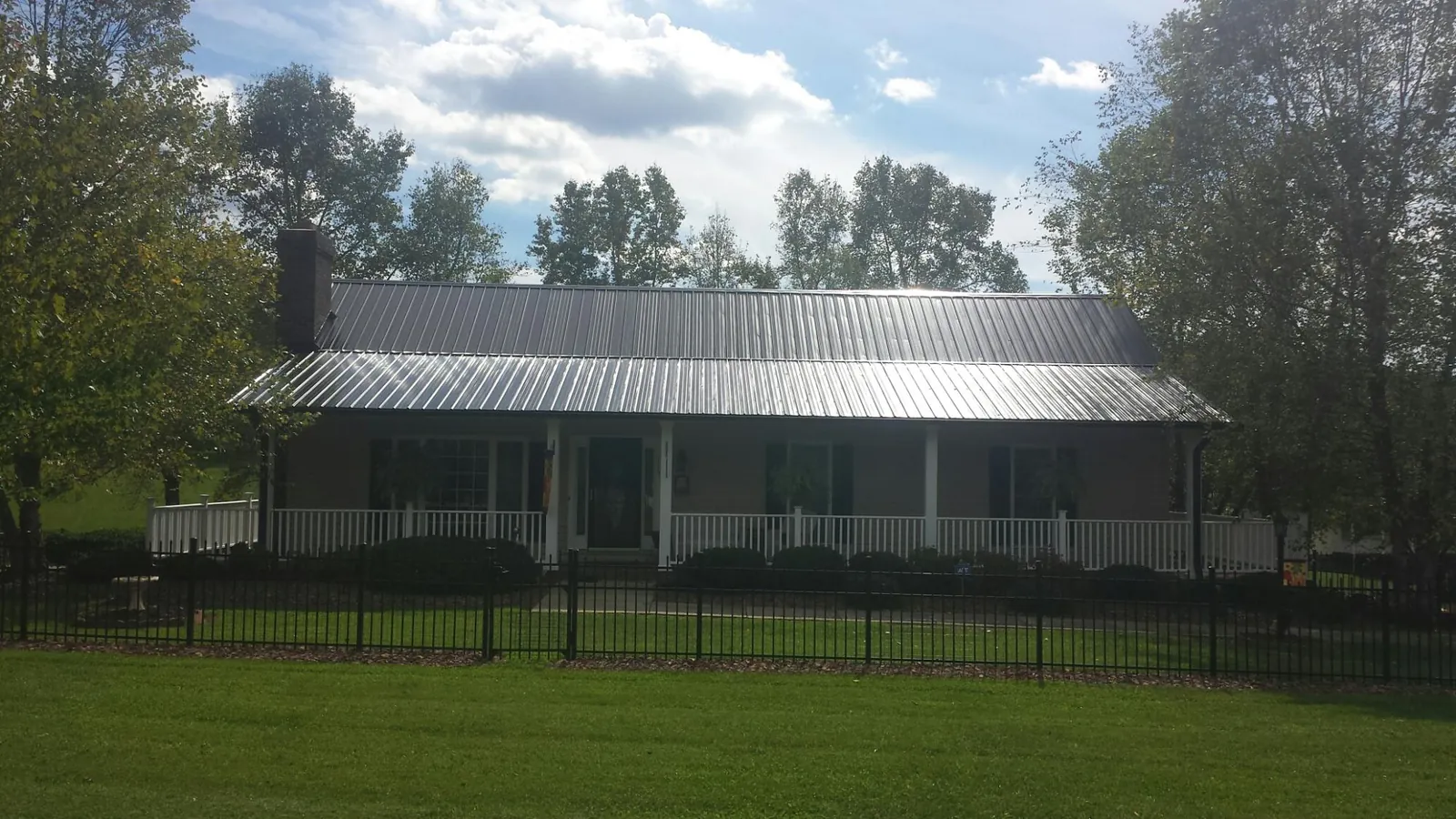 Gray metal roof on a brick ranch with a full width front porch — Gutter Guard Installation work by our crew in Longmeadow
