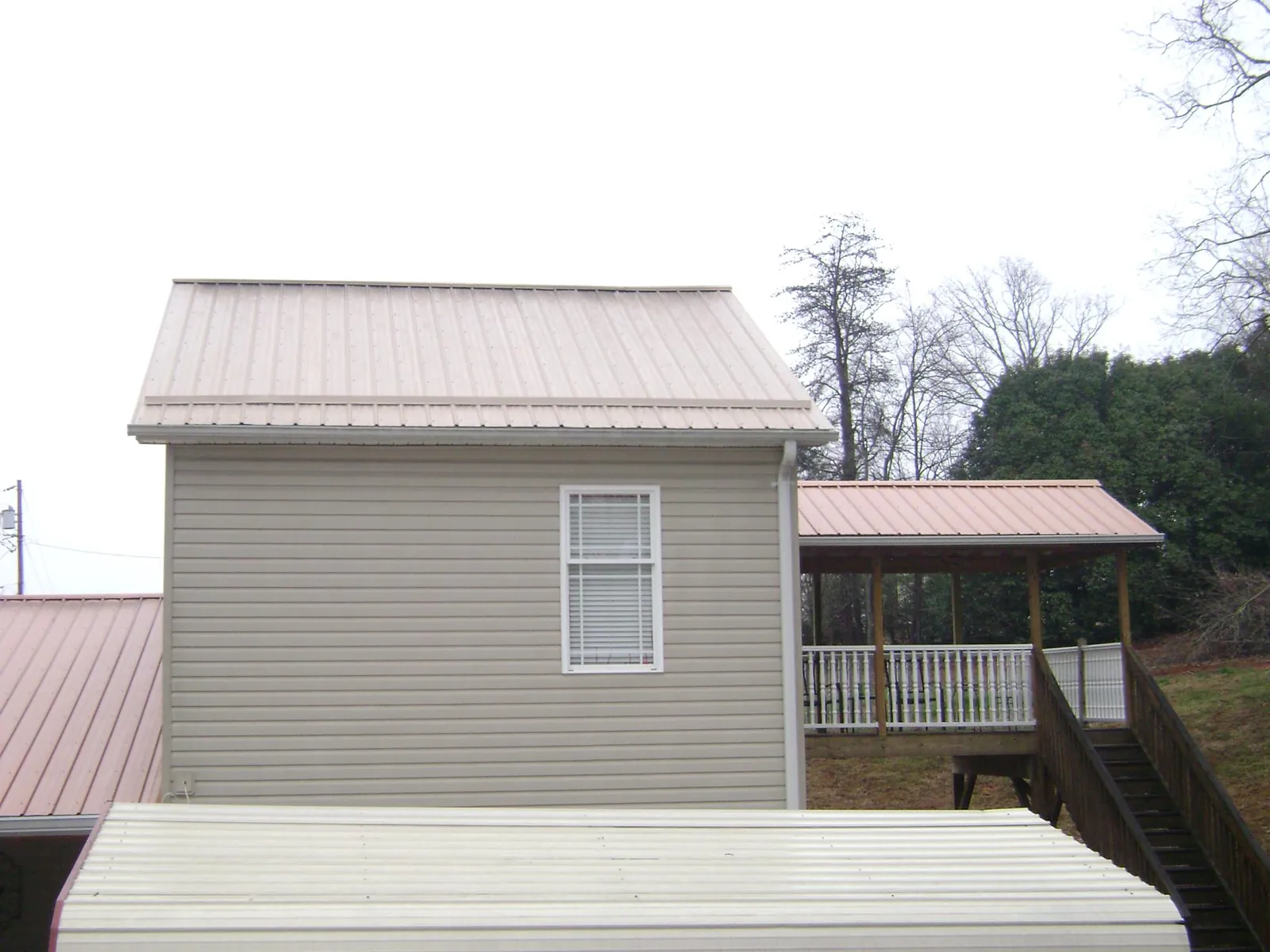 Tan metal roofs on a two story addition and attached porch, from a Roof Replacement job in Longmeadow