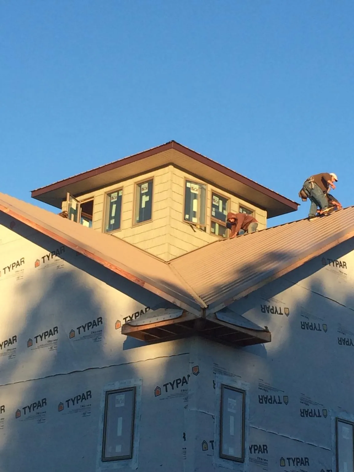 Roofers working around a rooftop cupola on a new metal roof at sunset — Roof Waterproofing in Longmeadow by Roofing Brothers